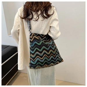Detailed view of the large tote bag with colorful wave patterns and a wide striped strap
