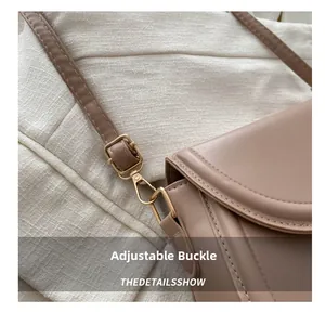 Détail de la boucle dorée réglable et de la bandoulière en cuir du sac besace marron