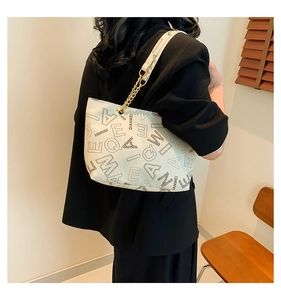 Detail of vintage beige shoulder bag featuring black letter prints and metal chain strap