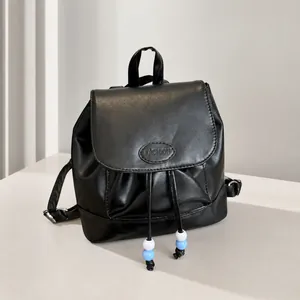 Detalle de la mochila de cuero negro con cierre de cordón y adornos de cuentas azules