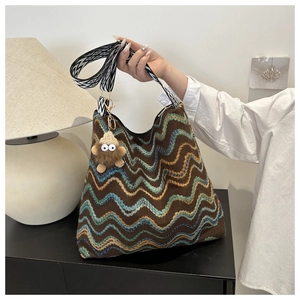 Detail of bohemian knit bucket bag with colorful wavy patterns and cute monster charm