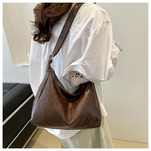 Grande borsa a tracolla marrone indossata da modella con ciondolo a forma di panda