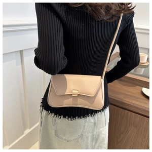 Beige rectangular shoulder bag with gold buckle worn with a black sweater and denim skirt