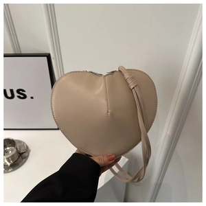 Détail du sac bandoulière beige en forme de cœur avec fermeture éclair et couture