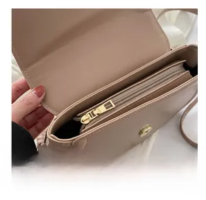 Détail du sac bandoulière beige minimaliste avec fermeture éclair dorée et fermoir magnétique