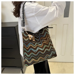 Detail of chevron knit bucket bag with geometric wide strap and plush pendant
