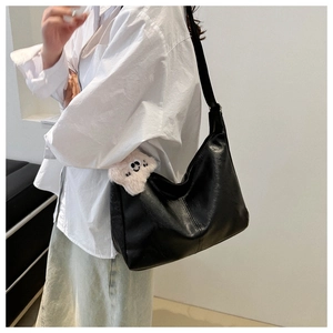 Dettaglio della grande borsa hobo nera minimalista con tracolla larga e trama in pelle