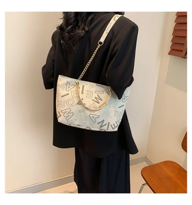 Detail of off-white tote bag with black letter print and elegant gold chain strap