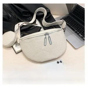 Detailed view of white pebble leather saddle bag with wide patterned strap and coin purse