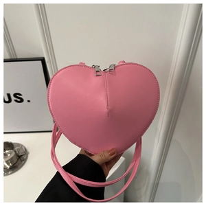 Détail du sac rose en forme de cœur montrant la texture du cuir PU et les doubles zips argentés
