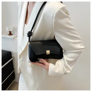 Detail of minimalist black leather handbag with gold buckle and knotted shoulder strap