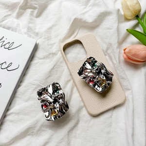 Chic cream leather phone case with ruffled metal gem grip holder on white fabric
