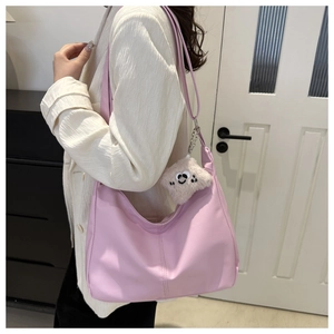 Borsa hobo rosa pallido in ecopelle con ciondolo di peluche indossata da modella