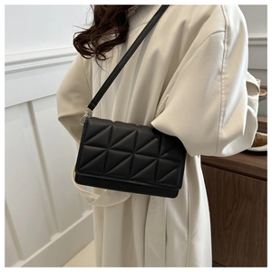 Detail of a black quilted crossbody bag showing triangular geometric patterns and silver hardware