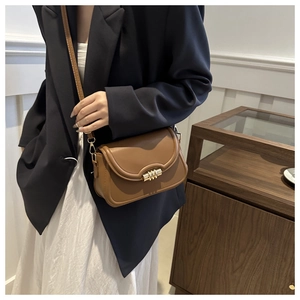 Vue détaillée du sac bandoulière marron avec une boucle cylindrique dorée distinctive