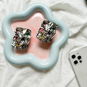 Close-up of silver crinkled metal phone grip with colorful square gemstones on blue tray