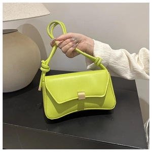 Detail of lime green crossbody bag featuring golden twist lock and knotted strap design