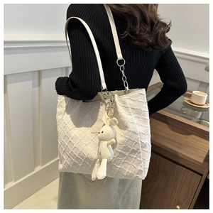 Détail du cabas blanc gaufré avec bandoulière en cuir et charm lapin en peluche