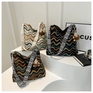 Ethnic knit bucket bag with colorful wavy patterns and plush charm on display