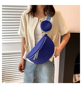 Blue crescent cross-body bag with woven strap and mini round pouch on a female model