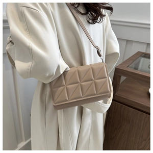 Detail of beige quilted square crossbody bag featuring 3D triangular embossed patterns