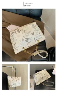 Detail view of cream tote bag with letter prints and gold chain strap in office setting