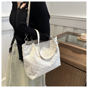 Detail showing the white knit texture and fluffy diamond fringe on this large tote bag
