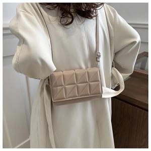Detail view of beige quilted small crossbody bag with textured triangular pattern on leather