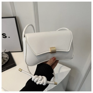 Detail of white minimalist baguette bag featuring a gold metal buckle and sleek leather finish