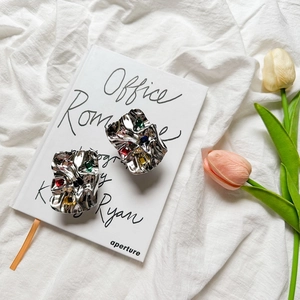 Close-up of silver irregular stud earrings with colorful gemstones and crumpled texture