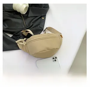 Detailed comparison of khaki nylon chest bag size with a smartphone on white background