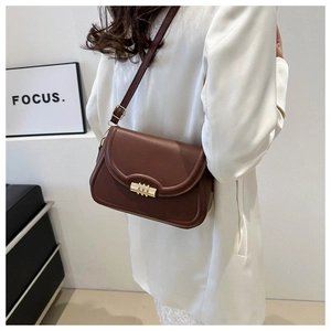 Détail du sac bandoulière en cuir marron foncé avec boucle dorée élégante à trois anneaux