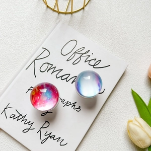 Detail shot of two crystal phone grips with blue and pink galaxy patterns on a book cover