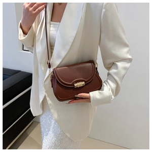 Détail du sac bandoulière en cuir marron foncé avec boucle dorée à trois anneaux et sangle