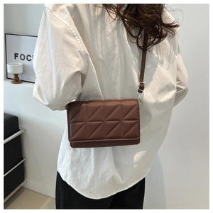 Detail of dark brown quilted square bag with silver hardware and adjustable shoulder strap