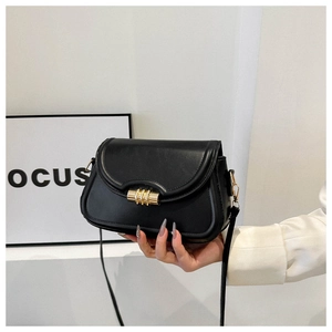 Détail d'un sac à bandoulière noir minimaliste avec une boucle en métal doré chic