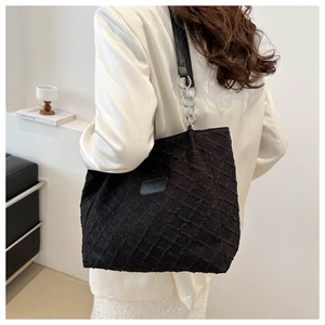 Detail of quilted large tote bag with textured rhombus pattern and silver chain strap