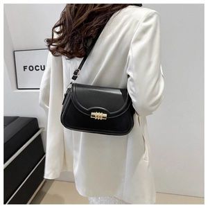 Détail d'un sac bandoulière noir minimaliste avec un fermoir en métal doré tubulaire