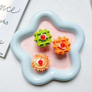 Top view of cherry cream waffle phone grip stand on a pastel petal-shaped ceramic plate