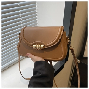 Gros plan d'un sac bandoulière marron avec boucle dorée et rabat en forme de selle