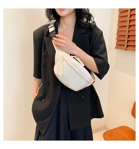 White nylon sling bag with wide strap and plastic buckle worn with black blazer
