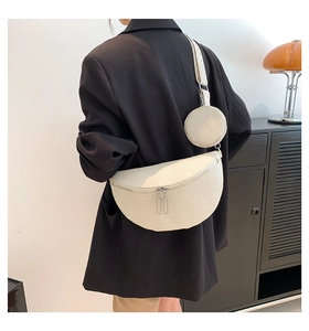 Close-up of white pebble grain saddle bag with round coin purse and woven strap