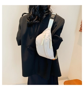 Rear view of a model wearing a light beige nylon crossbody bag with adjustable wide strap
