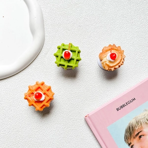 Detailed view of three resin cherry cream waffle and tart phone grip stands on a tray