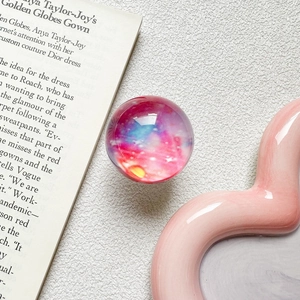 Detail shot of the crystal ball phone grip with galaxy pattern on a wavy pink tray