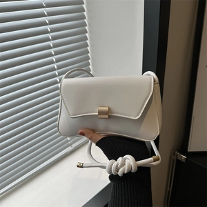 Minimalist white leather crossbody bag with a gold square buckle and knotted strap