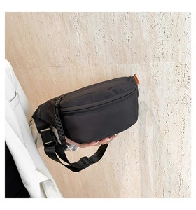 Detail of black nylon fanny pack with quick-release buckle and orange woven label