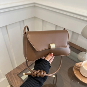 Minimalist caramel brown leather crossbody bag with adjustable knot strap and gold buckle