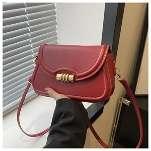 Détail du sac bandoulière en cuir rouge avec un fermoir métallique doré sophistiqué