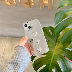 Mirror iPhone case with three 3D silver heart ornaments and clear edges in hand-held view